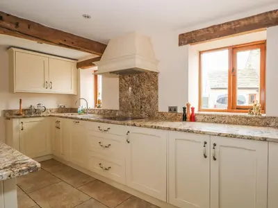 a kitchen with white cabinets and a window at Rose Hips Barn in Chorley