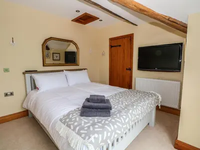 a bedroom with a bed and a flat screen tv at Rose Hips Barn in Chorley