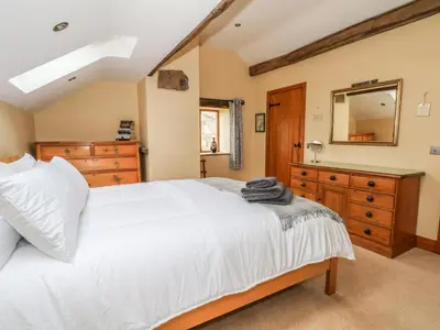a bedroom with a white bed and a dresser and a mirror at Rose Hips Barn in Chorley