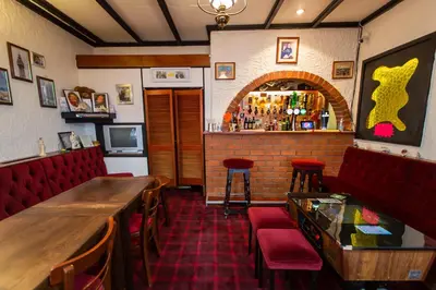a restaurant with a bar with red chairs and a counter at The Ferndale Hotel in Blackpool