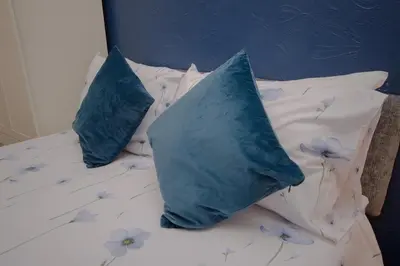two blue pillows on a bed with flowers on it at The Ferndale Hotel in Blackpool