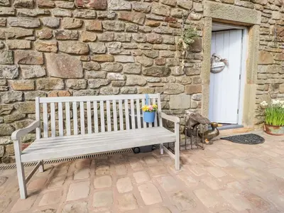 a wooden bench sitting in front of a stone wall at The Boot Room in Preston