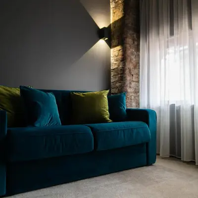 a blue couch in a living room with a window at The Baltic Hotel in Liverpool