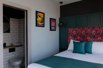 a bedroom with a bed with a green headboard and a toilet at The Baltic Hotel in Liverpool