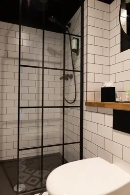 a shower in a bathroom with white tiles at The Baltic Hotel in Liverpool