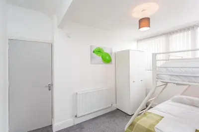 a white bedroom with a bunk bed and a ladder at Cherry Property - Hornby Road in Blackpool