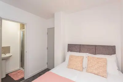 a white bedroom with a bed and a sink at Cherry Property - Hornby Road in Blackpool