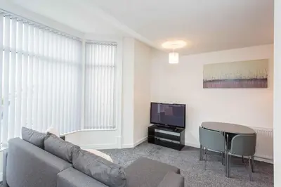 a living room with a couch and a table and a tv at Cherry Property - Hornby Road in Blackpool
