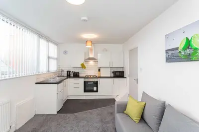 a kitchen with white cabinets and a couch in a room at Cherry Property - Hornby Road in Blackpool