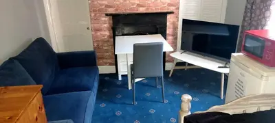a living room with a blue couch and a fireplace at Phoenix Nights Guest House in Barrow in Furness