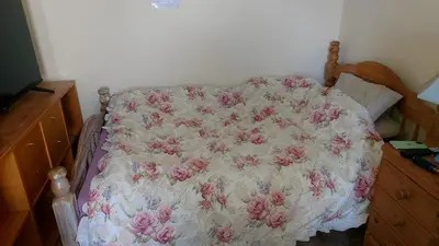 a bed with a pink and white comforter on it at Phoenix Nights Guest House in Barrow in Furness