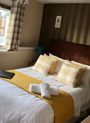 a bedroom with a large bed with two towels on it at Adelphi Guest House in Southport