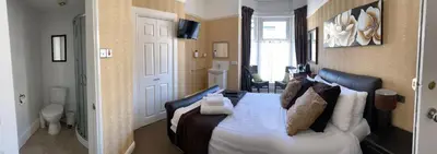 a bedroom with a bed with white sheets and pillows at Adelphi Guest House in Southport