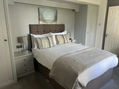 a bedroom with a large bed and a night stand at Uplands Inn Cartmel in Cartmel