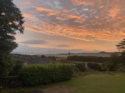 a sunset over a field with bushes and trees at Uplands Inn Cartmel in Cartmel