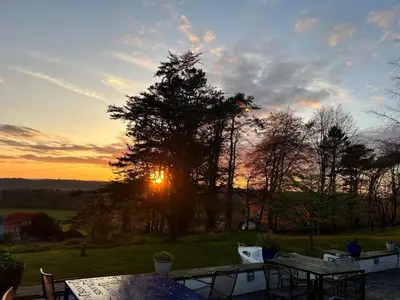a sunset behind a tree with a table and chairs at Uplands Inn Cartmel in Cartmel