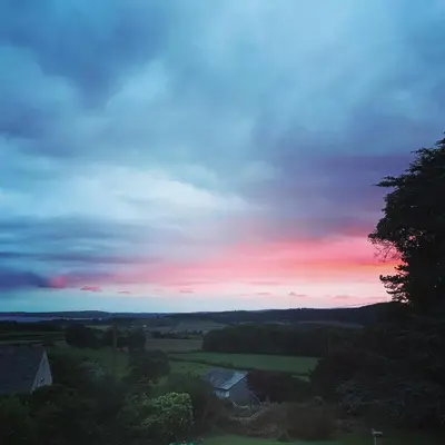 a sunset in the sky over a field at Uplands Inn Cartmel in Cartmel