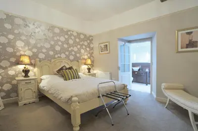 a bedroom with a bed and two tables and a chair at Priory hotel in Cartmel