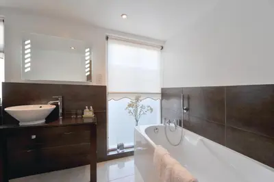 a bathroom with a tub and a sink and a mirror at Priory hotel in Cartmel