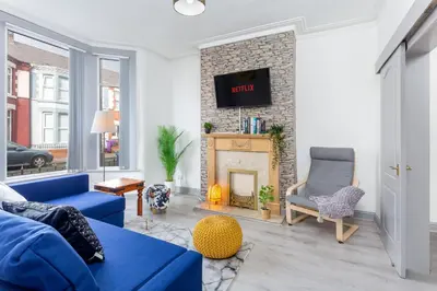 a living room with a blue couch and a fireplace at Superb Spacious House For Contractors & Families & Private Parking By Liverpool Short Stay in Liverpool