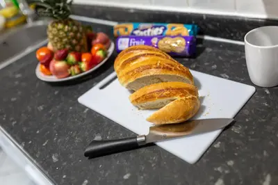 a loaf of bread on a cutting board with a knife at Superb Spacious House For Contractors & Families & Private Parking By Liverpool Short Stay in Liverpool