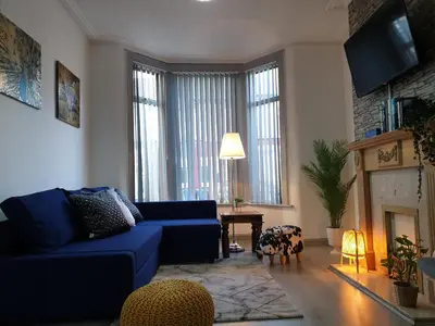 a living room with a blue couch and a fireplace at Superb Spacious House For Contractors & Families & Private Parking By Liverpool Short Stay in Liverpool