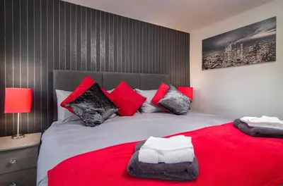 a bedroom with a large bed with red and black pillows at 2 Bedrooms Sleeps 6 Near Top Blackpool Attractions in Blackpool