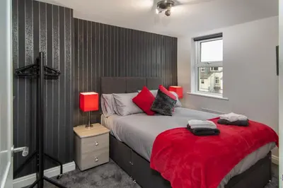 a bedroom with a large bed with a red blanket at 2 Bedrooms Sleeps 6 Near Top Blackpool Attractions in Blackpool