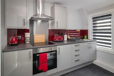 a kitchen with white cabinets and red towels at 2 Bedrooms Sleeps 6 Near Top Blackpool Attractions in Blackpool
