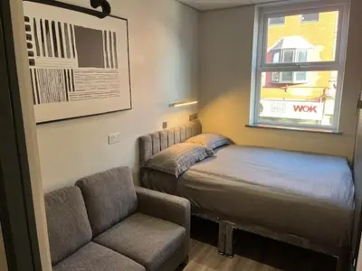 a bedroom with a bed and a couch and a window at The Anfield Rooms in Liverpool