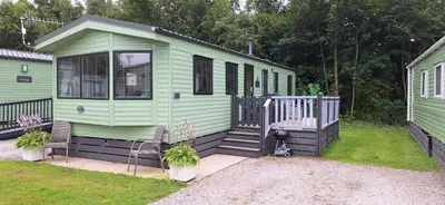 a green house with a porch and stairs in a yard at Inside No. 9 Retreat in Carnforth