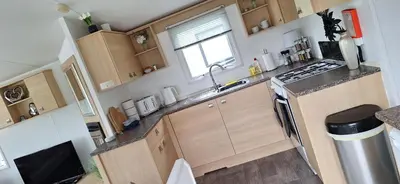 a small kitchen with wooden cabinets and a sink at Inside No. 9 Retreat in Carnforth