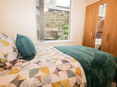 a bedroom with a bed with a quilt and a window at Cosy Bee in Morecambe