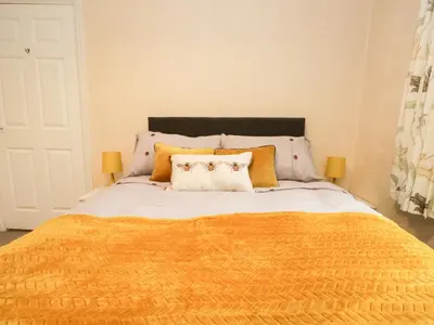 a bed with an orange blanket and two pillows at Cosy Bee in Morecambe