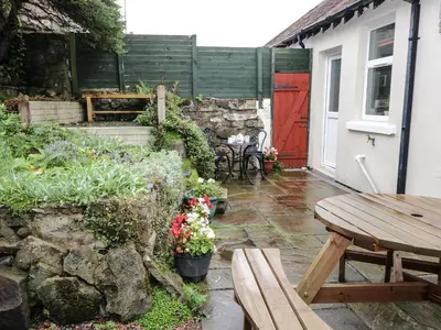 a patio with a wooden table and a red door at Cosy Bee in Morecambe