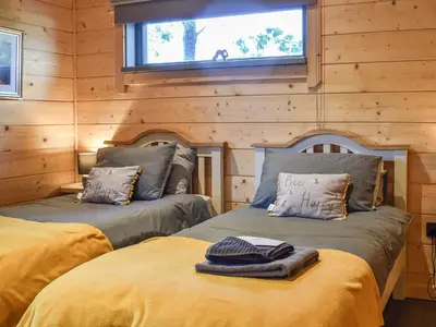 two beds in a log cabin with a window at Oak Lodge - Uk30005 in Lindal in Furness
