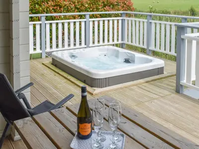 a bottle of wine sitting on a table next to a hot tub at Birch Lodge - Uk30006 in Lindal in Furness