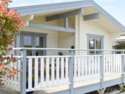 a cottage with a white railing and a porch at Birch Lodge - Uk30006 in Lindal in Furness