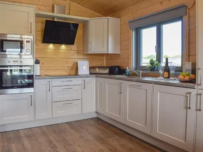 a kitchen with white cabinets and a sink and a window at Birch Lodge - Uk30006 in Lindal in Furness