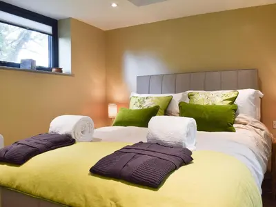 a bedroom with a large bed with green pillows at The Bothy in Beetham