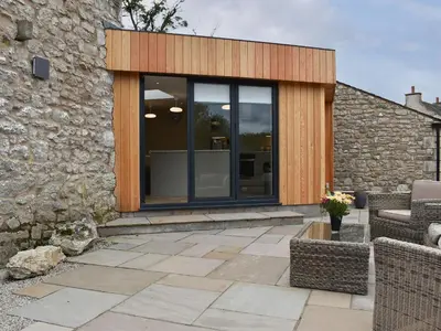 a glass extension to a house with a stone wall at The Bothy in Beetham