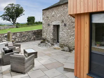 a patio with chairs and a stone building at The Bothy in Beetham
