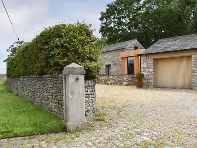 a stone wall next to a house with a garage at The Bothy in Beetham
