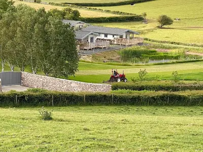 a person riding a tractor in a field at Pine Lodge - Uk30007 in Lindal in Furness