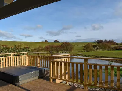 a wooden deck with a table and a pond at Larch Lodge - Uk30009 in Lindal in Furness