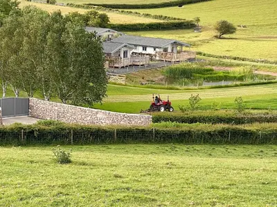 a person riding a tractor in a field at Larch Lodge - Uk30009 in Lindal in Furness