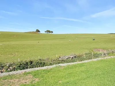a green field with animals grazing in the distance at Larch Lodge - Uk30009 in Lindal in Furness