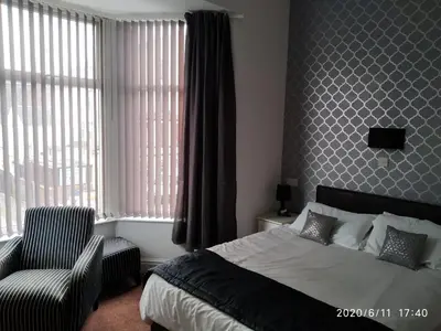 a bedroom with a bed and a chair and window at Mardi Gras Hotel in Blackpool