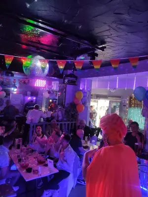 a group of people sitting at tables in a party at Mardi Gras Hotel in Blackpool