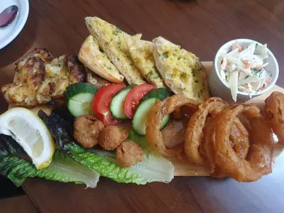 a plate of food with onion rings and vegetables at Mardi Gras Hotel in Blackpool